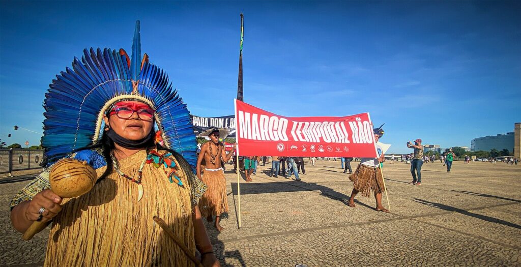 An Indigenous woman, with a traditional headdress, protests against the Marco Temporal thesis in Brasilia.