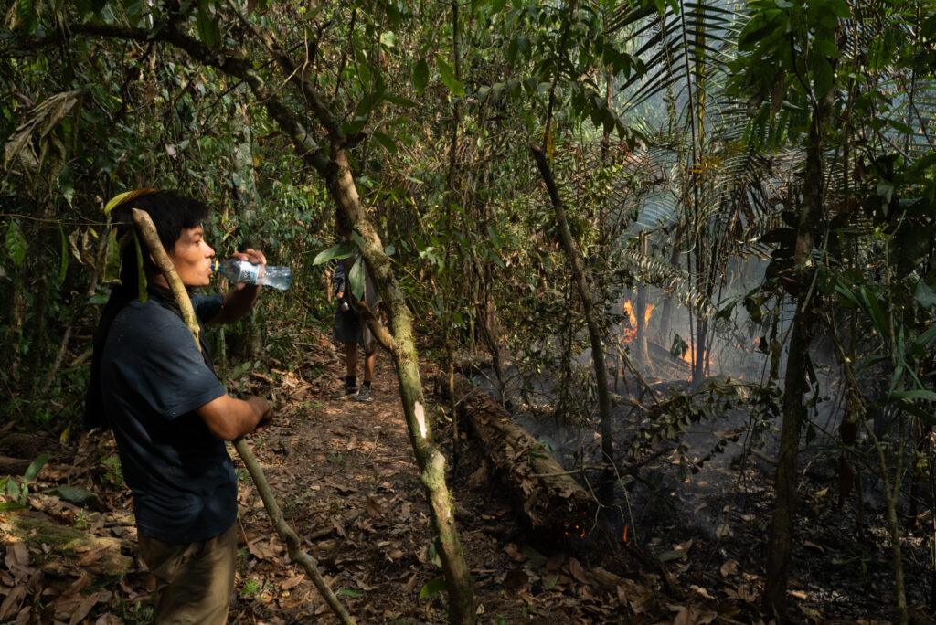 Yoweki Piyãko drinks water after fighting a nearby fire in the forest.