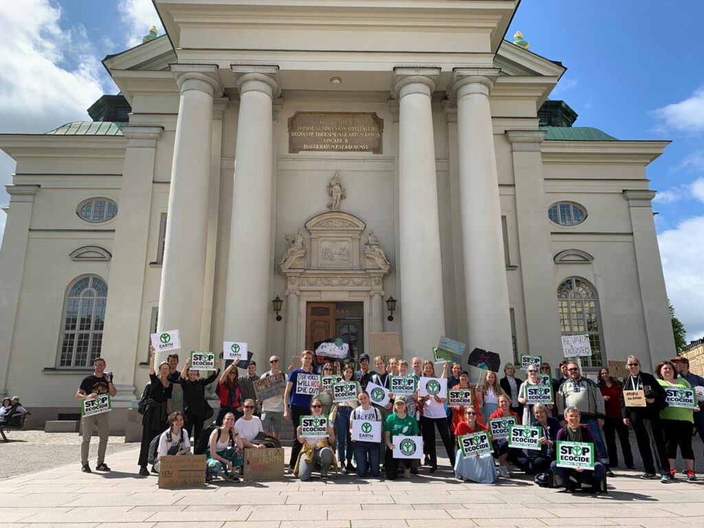 A group of protestors gathered in Stockholm, holding "Stop Ecocide" placards.